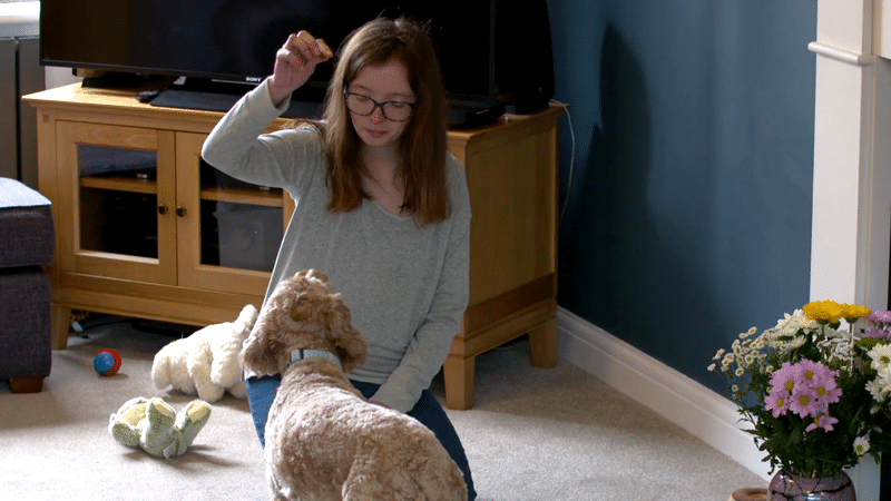 Georgia, a child with the rare chromosomal condition Silver-Russell syndrome, playing with her dog in her home.